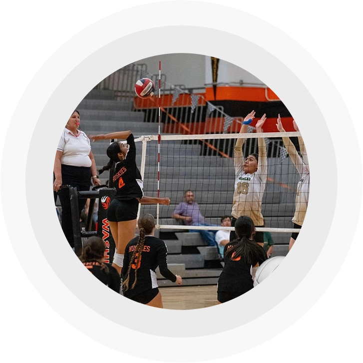 A group of people playing volleyball in an arena.