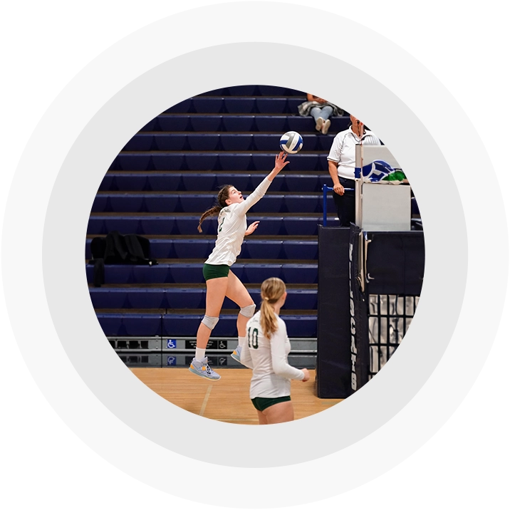 A girl jumps to hit the ball during a volleyball game.