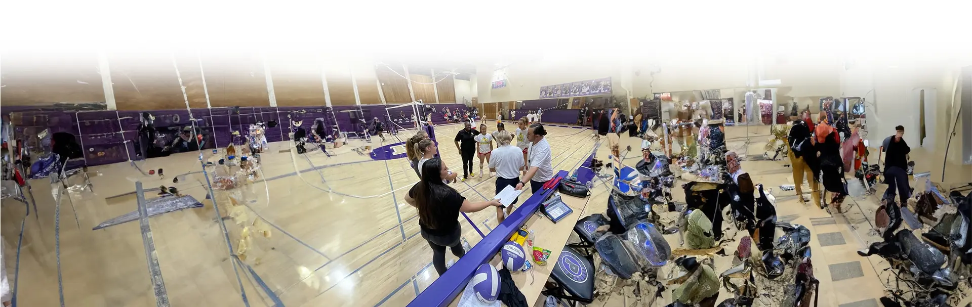 A group of people standing around in an indoor gym.